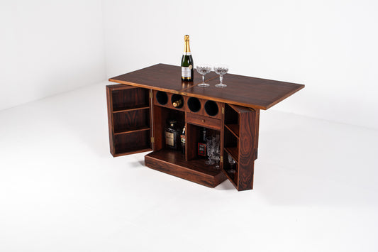 Vintage Danish rosewood dry bar cabinet with both doors open, revealing built-in bottle storage, shelving, drawers, and compartments for glassware and spirits.