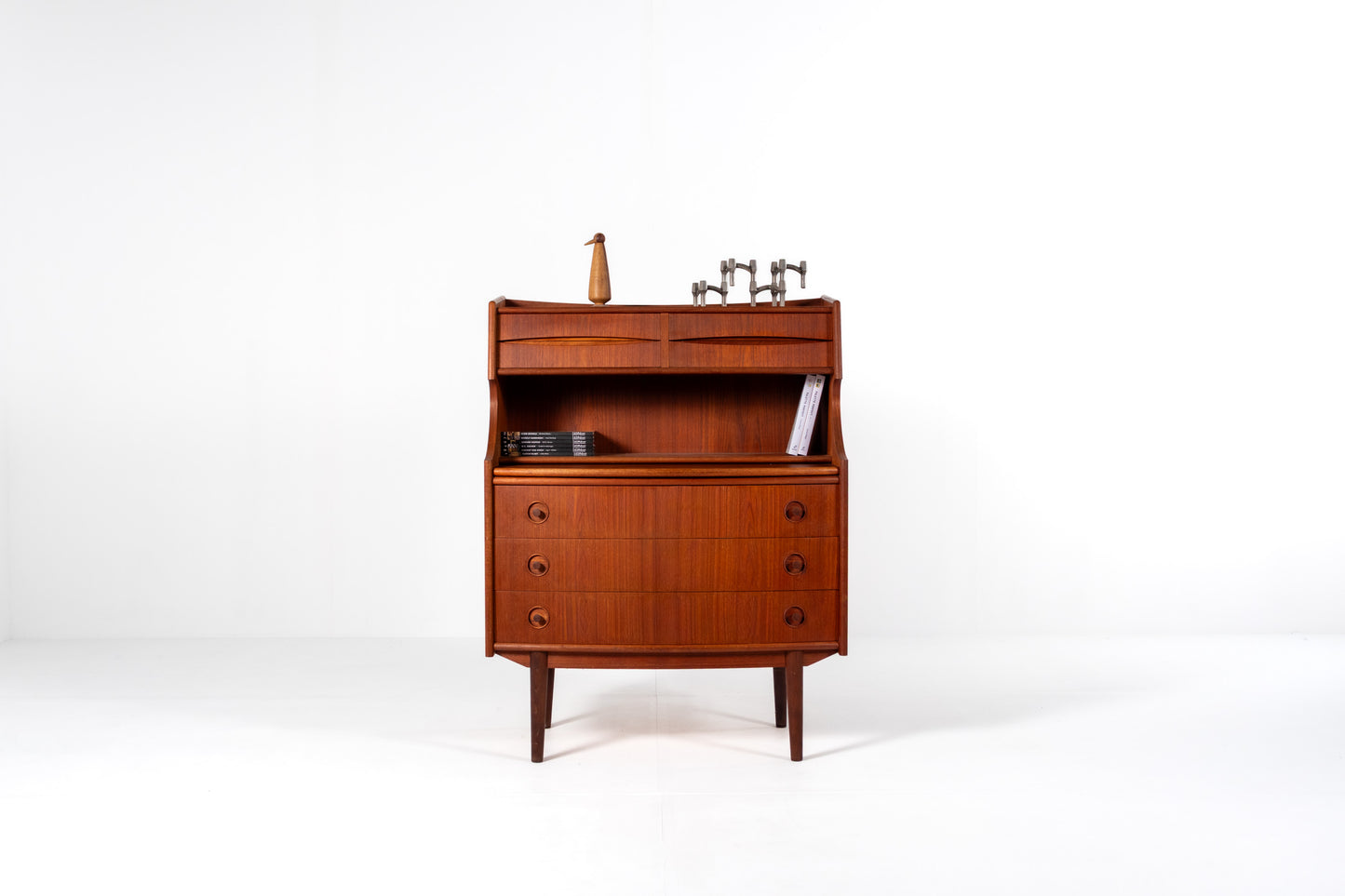 A mid-century modern wooden writing desk by Gunnar Falsig for Falsig Møbler with a warm reddish-brown finish, featuring a curved front, three drawers, and an open upper shelf 