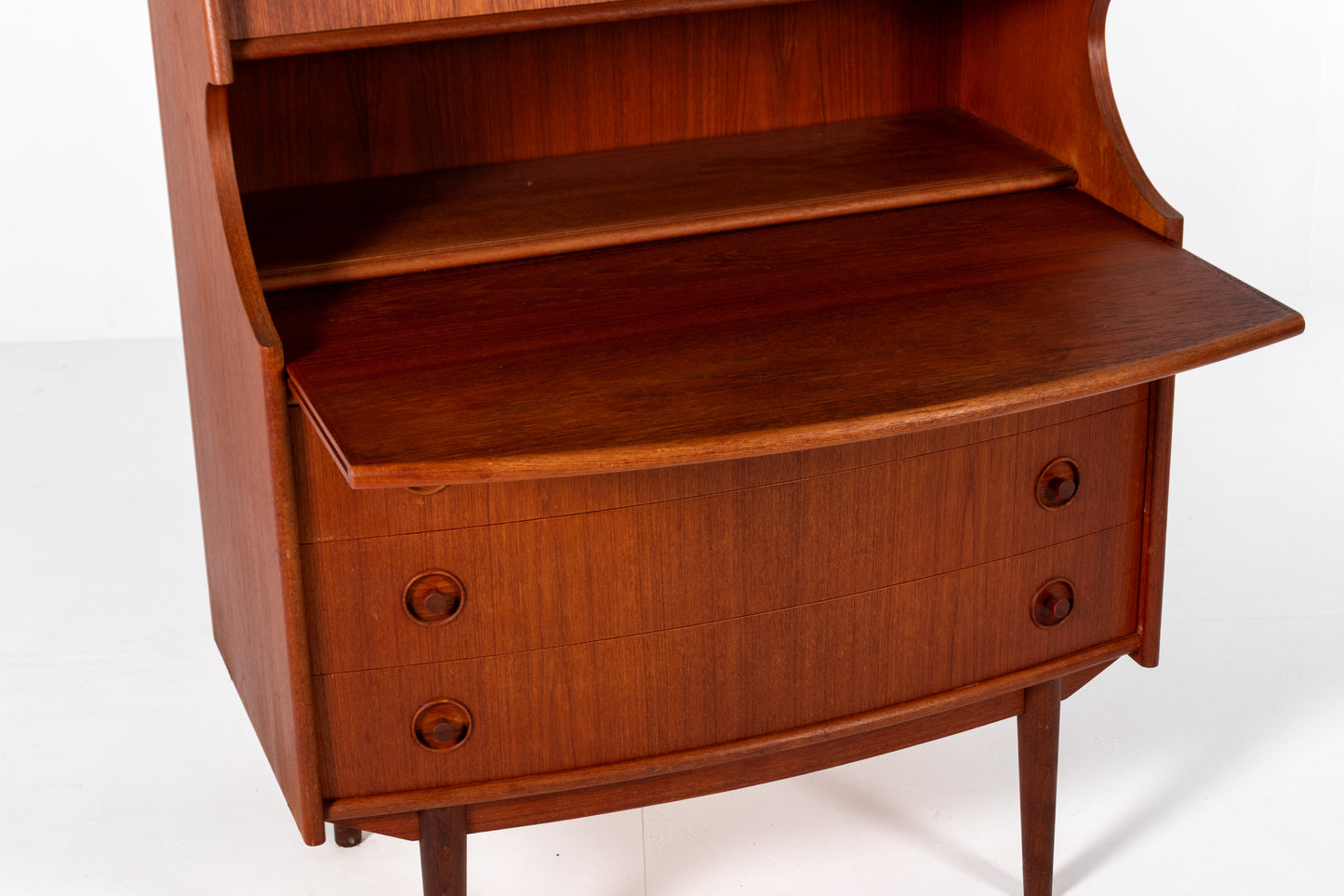 Mid-century modern wooden writing desk by Gunnar Falsig for Falsig Møbler with a warm reddish-brown finish, featuring a curved front drawer base, round drawer knobs, and a partially open top hutch shelf.