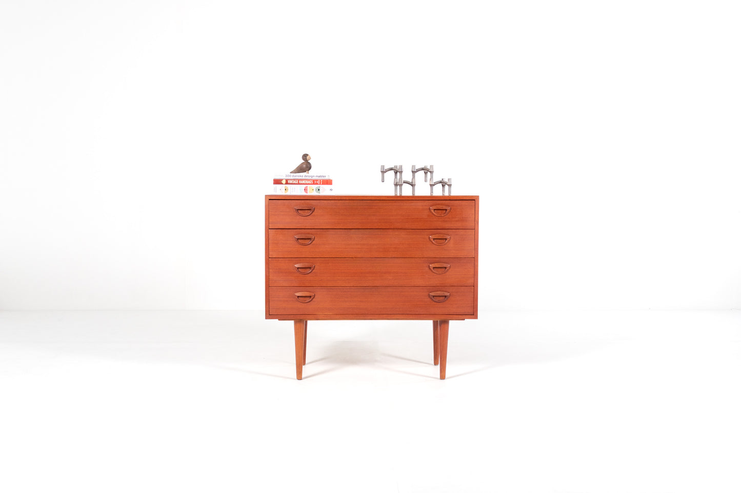A mid-century modern wooden chest of drawers with five drawers by Kai Kristiansen, shown against a plain white studio background. 