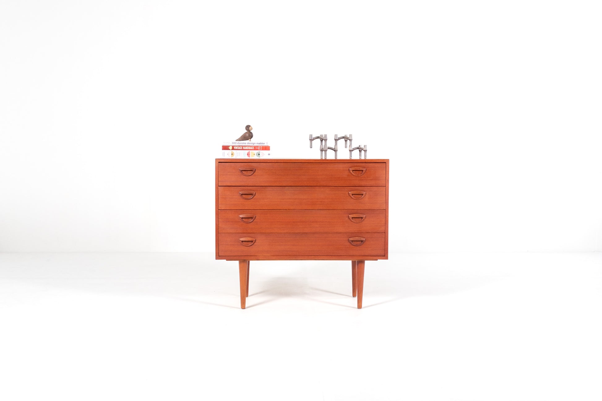A mid-century modern wooden chest of drawers with five drawers by Kai Kristiansen, shown against a plain white studio background. 