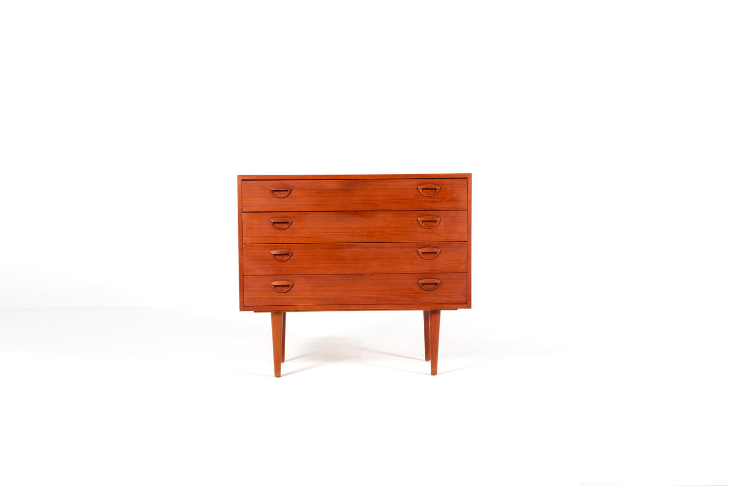 A mid-century modern wooden chest of drawers with five drawers by Kai Kristiansen, shown against a plain white studio background. 