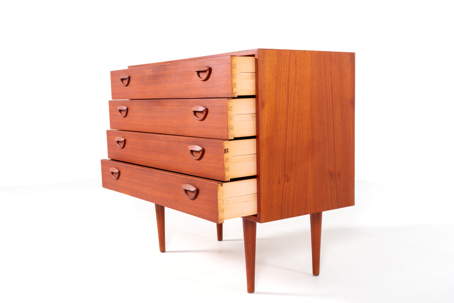 A mid-century modern wooden chest of drawers with five drawers by Kai Kristiansen, shown against a plain white studio background. 