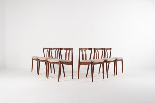 Six mid-century modern dining chairs  by Kai Kristiansen with dark brown teak frames and light grey upholstered seats, arranged in two pairs on a white studio background.