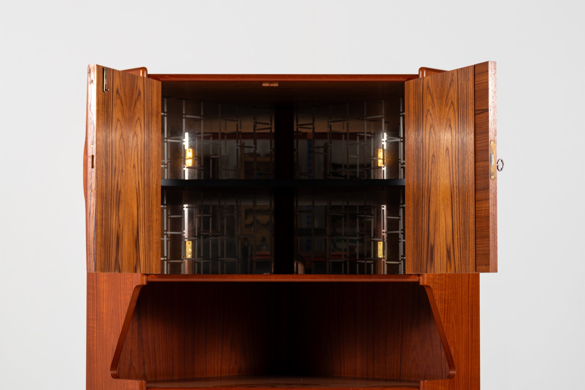 A mid-century modern wooden cabinet with two doors swung open, showcasing a dark wood grain finish, glass-front interior shelves, and a lower open storage compartment, set against a plain light gray background.