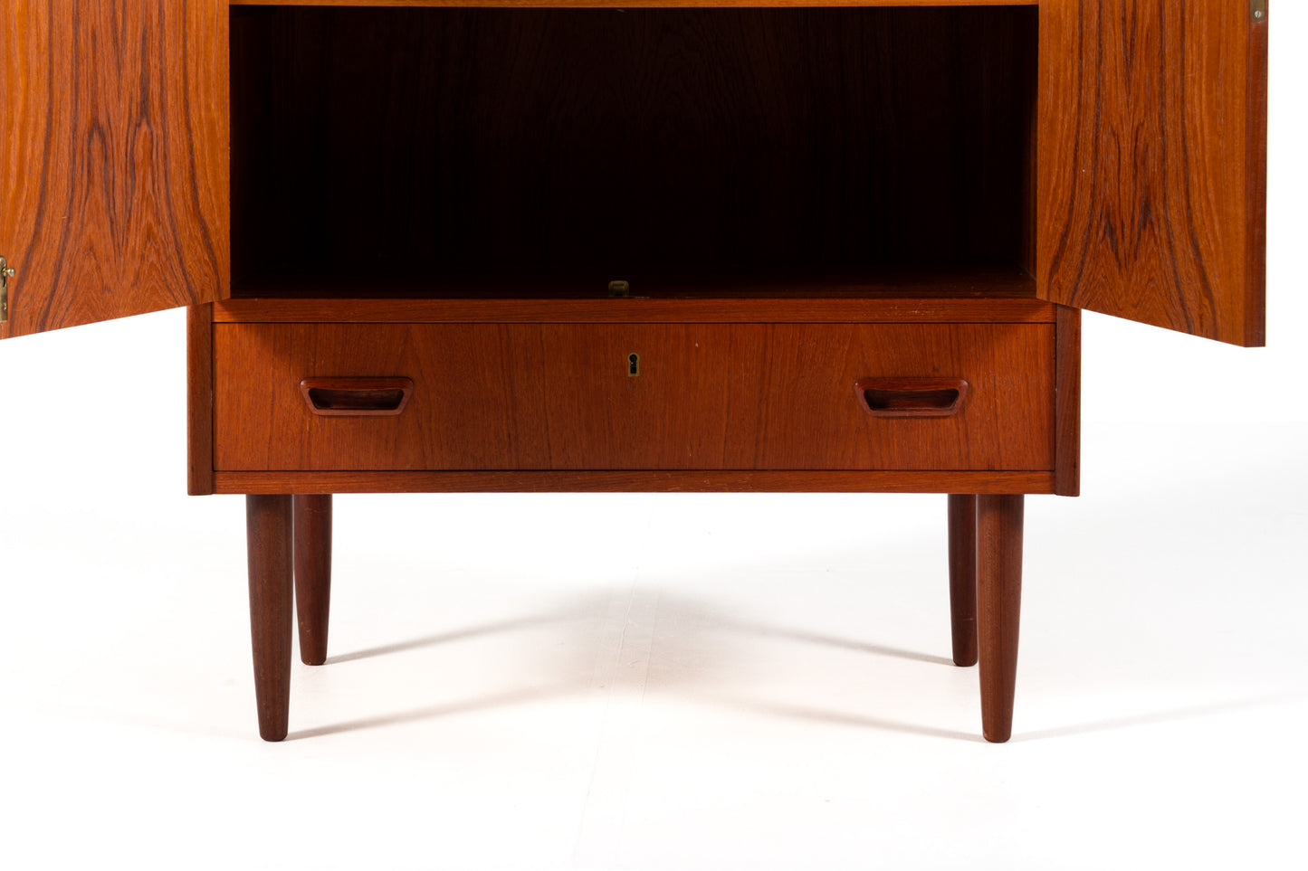 A mid-century modern wooden cabinet with a warm reddish-brown finish, featuring two upper doors and a lower drawer