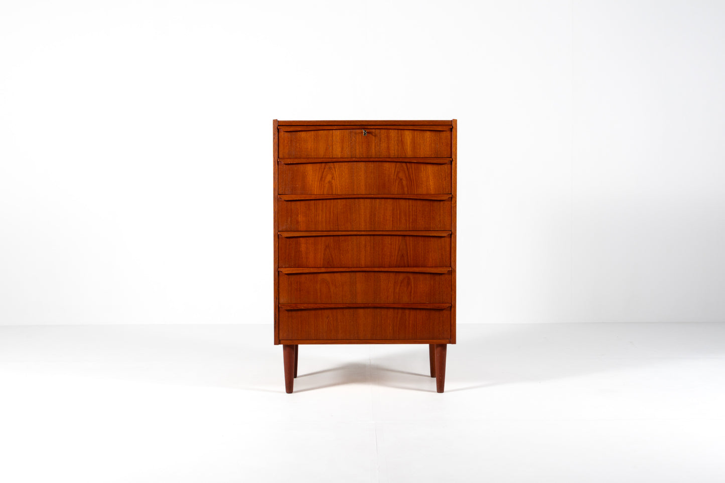 A mid-century modern wooden chest of drawers with five curved front drawers, shown on a clean white studio background.