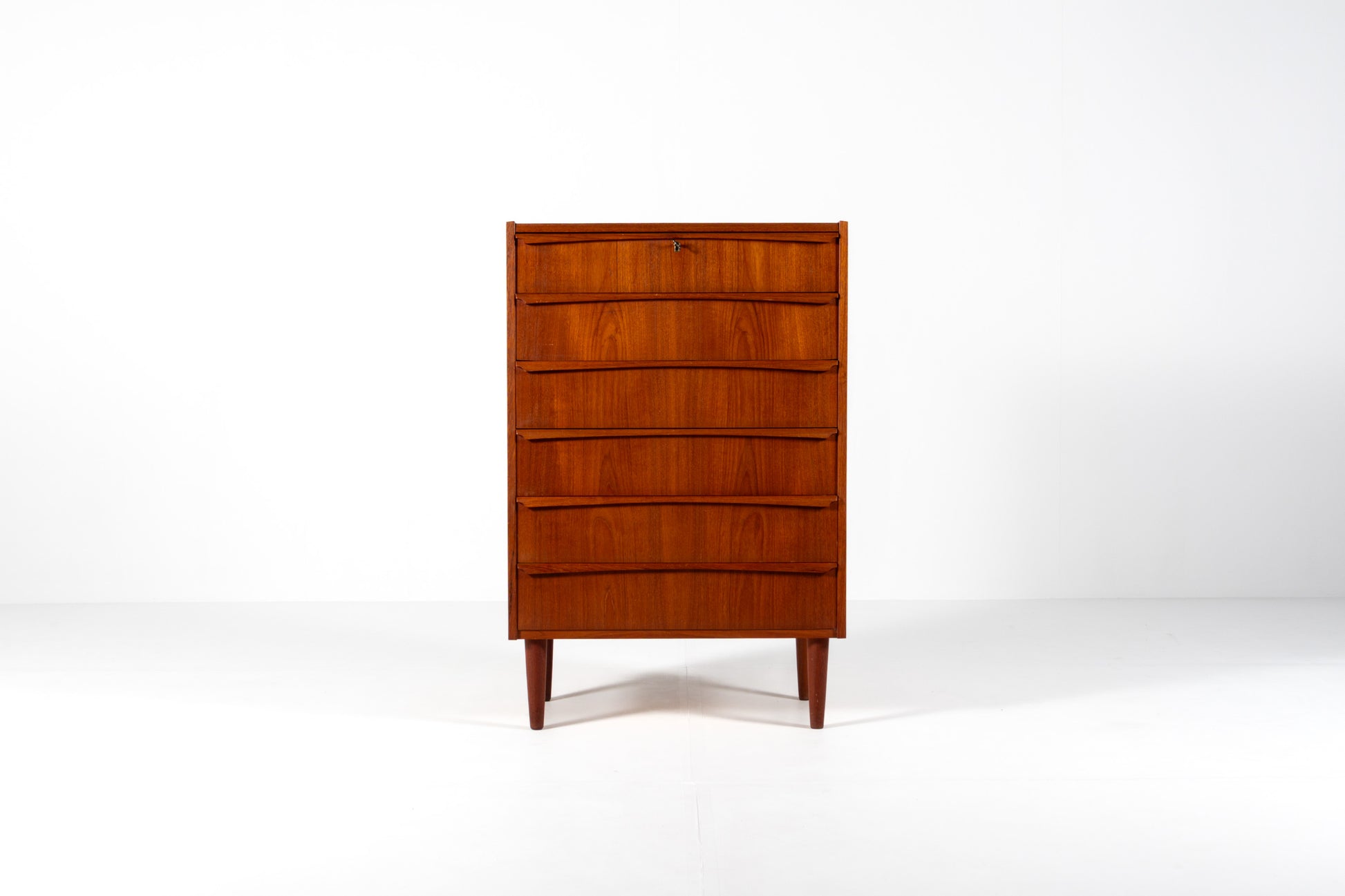 A mid-century modern wooden chest of drawers with five curved front drawers, shown on a clean white studio background.