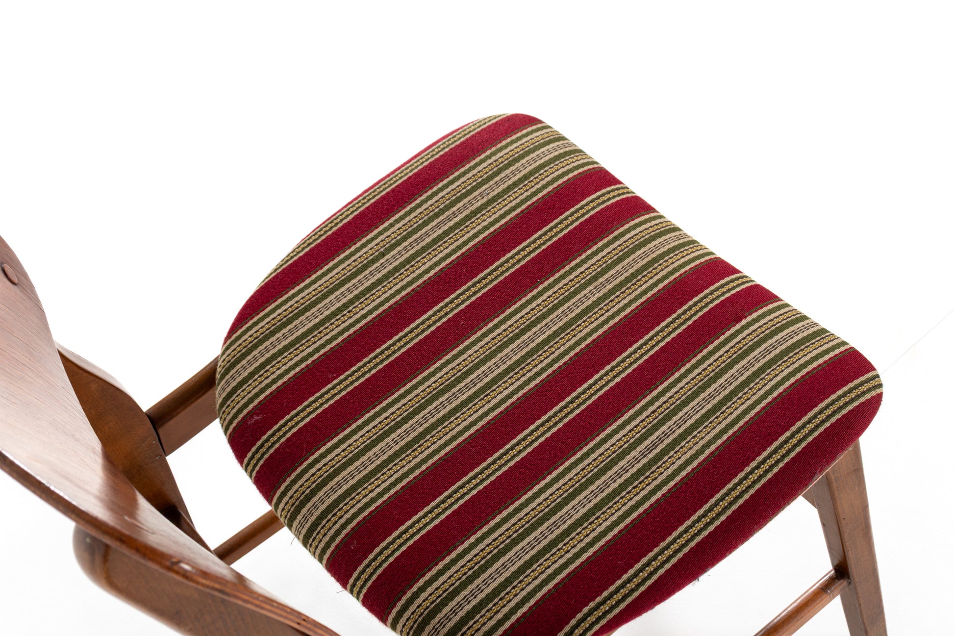 A close-up of a striped upholstered chair cushion in red, beige, and olive green, mounted on vintage Danish dining chairs.
