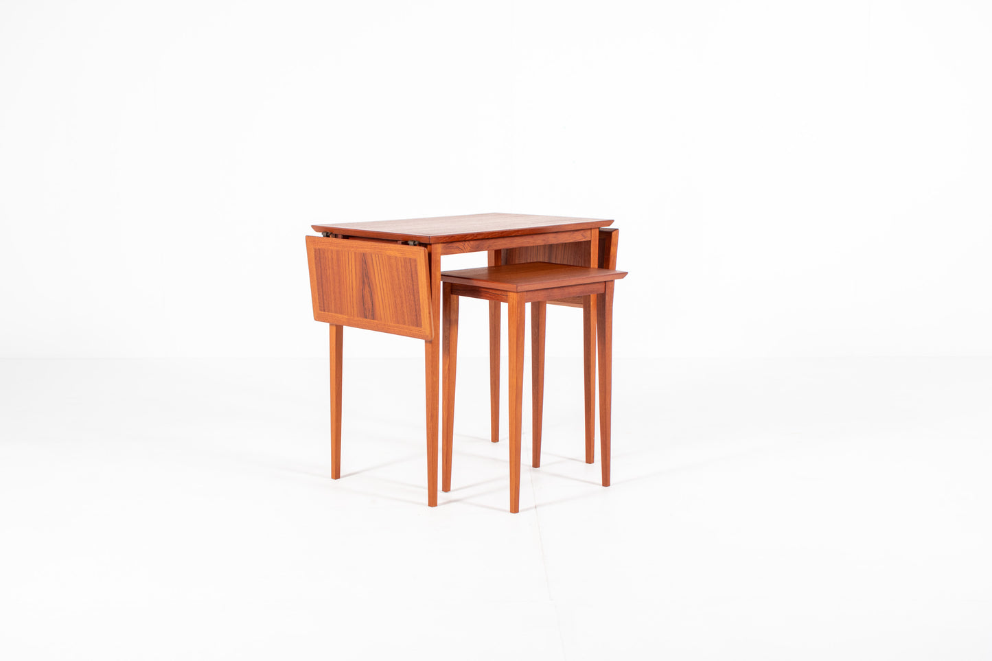 1960s Scandinavian teak nesting tables in their compact configuration, highlighting the clean lines and minimalist Danish craftsmanship.