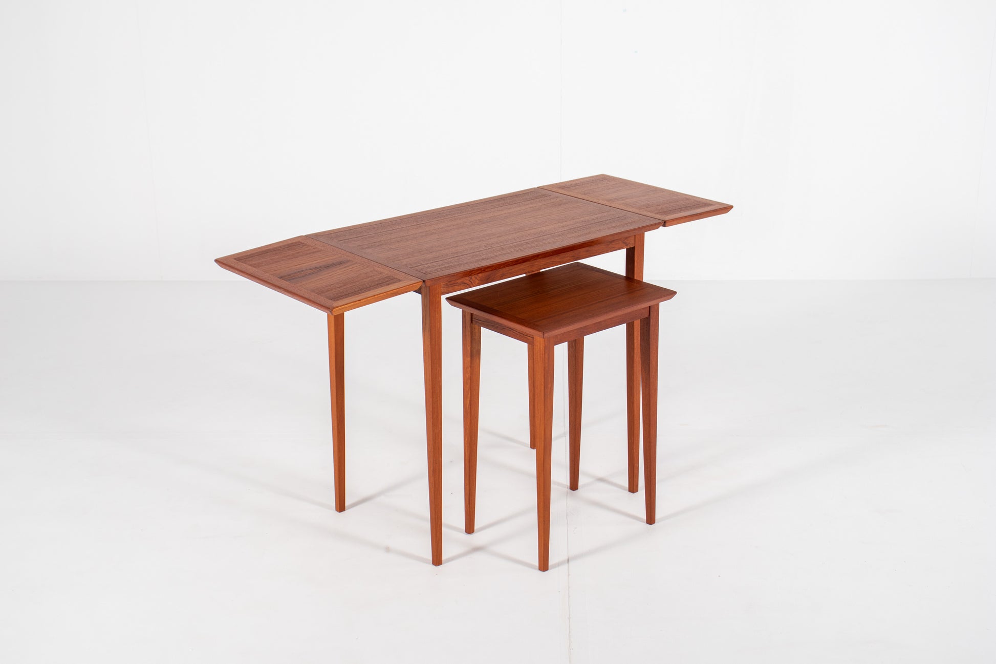 Vintage Danish nesting table with both drop leaves fully extended, demonstrating the versatile space-saving design.