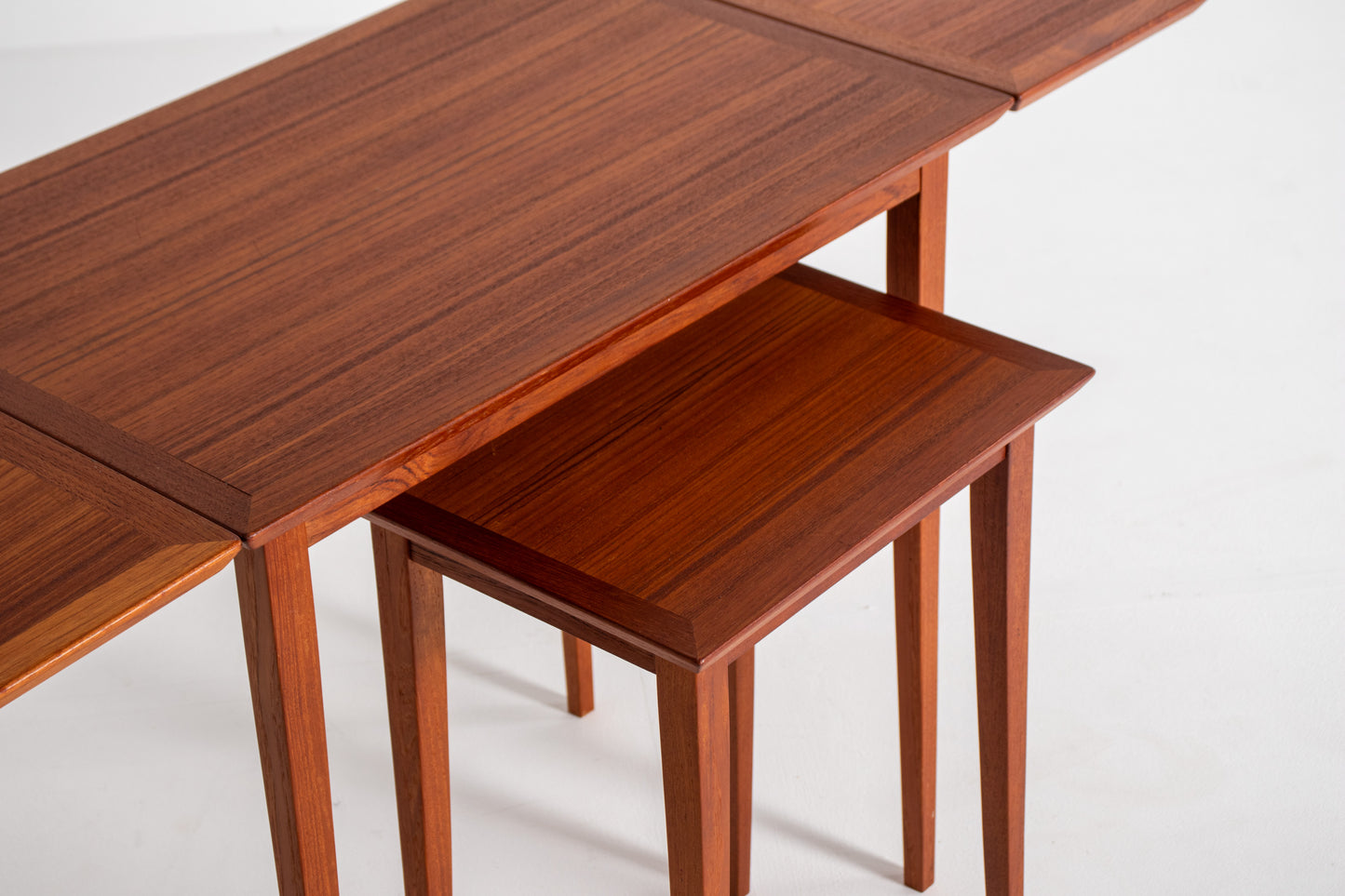 Close-up of the rich teak wood grain and finely crafted edges of a vintage Scandinavian nesting table.