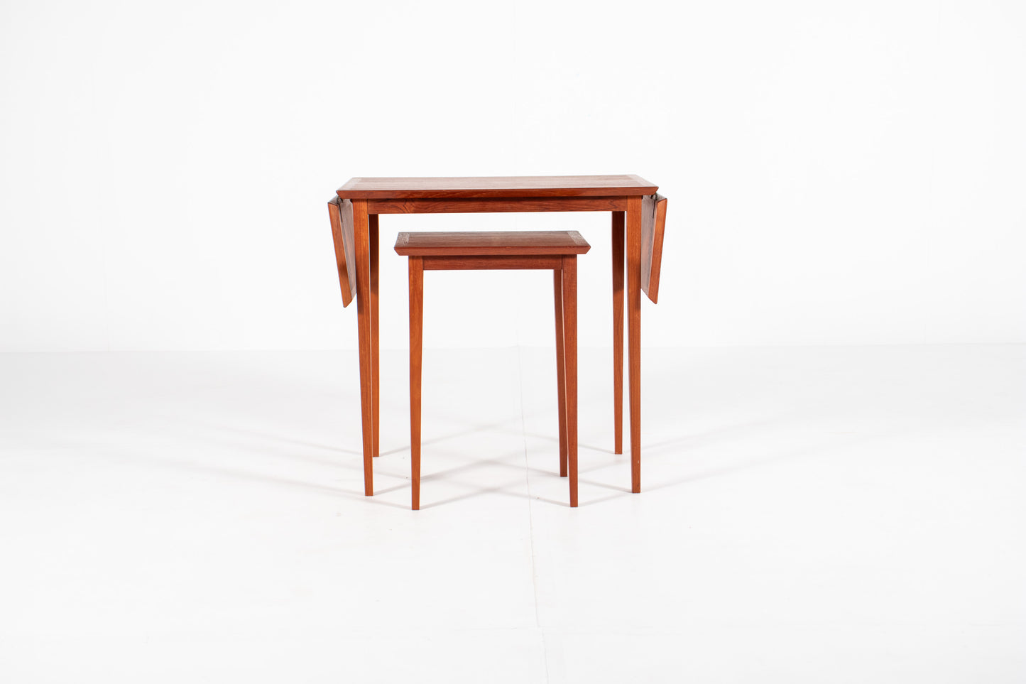 1960s Scandinavian teak nesting tables in their compact configuration, highlighting the clean lines and minimalist Danish craftsmanship.