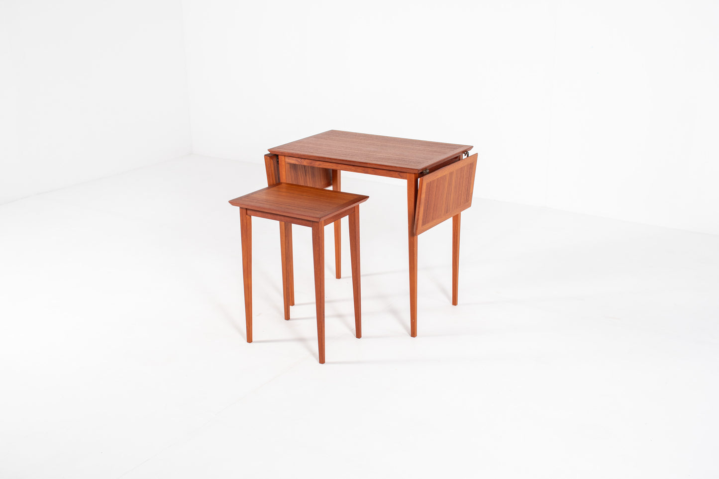 1960s Scandinavian teak nesting tables in their compact configuration, highlighting the clean lines and minimalist Danish craftsmanship.