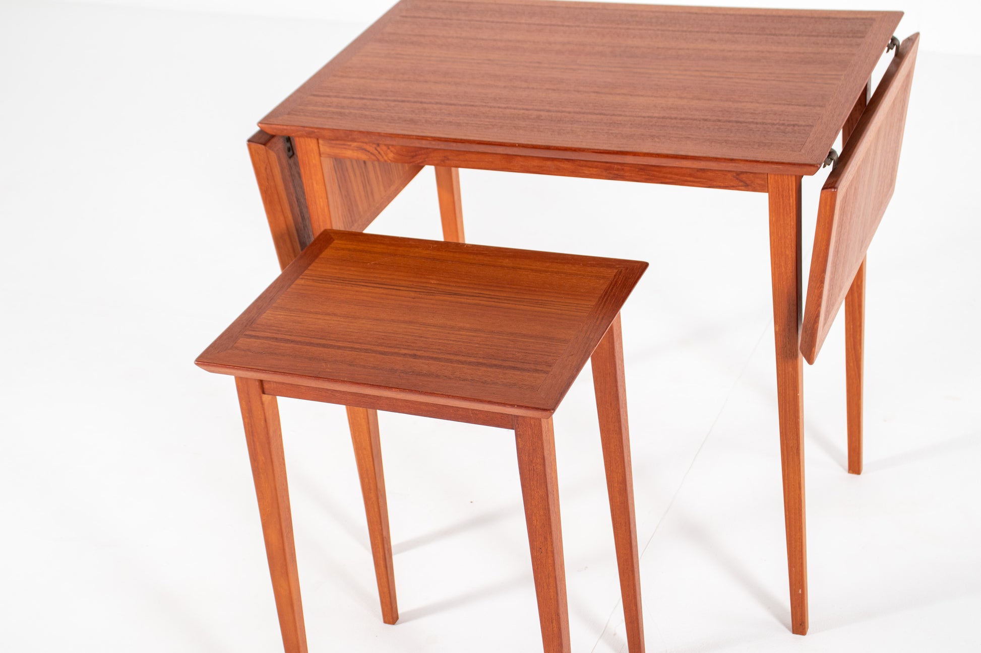 Close-up of the rich teak wood grain and finely crafted edges of a vintage Scandinavian nesting table.