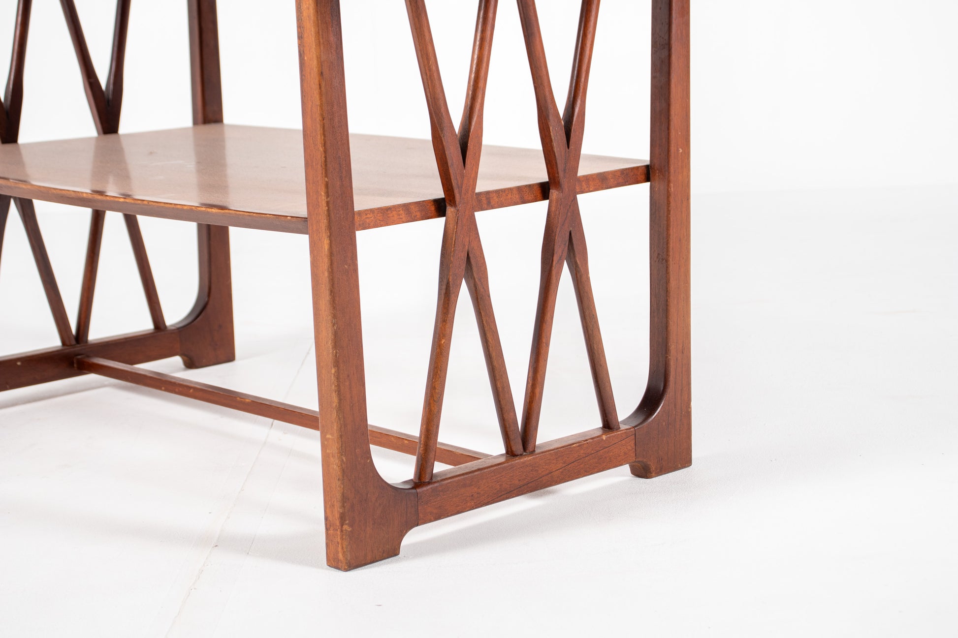 A close-up of a mid-century modern wooden table  designed by A.A. Patijn for Zijlstra Joure  featuring geometric crisscross supports .