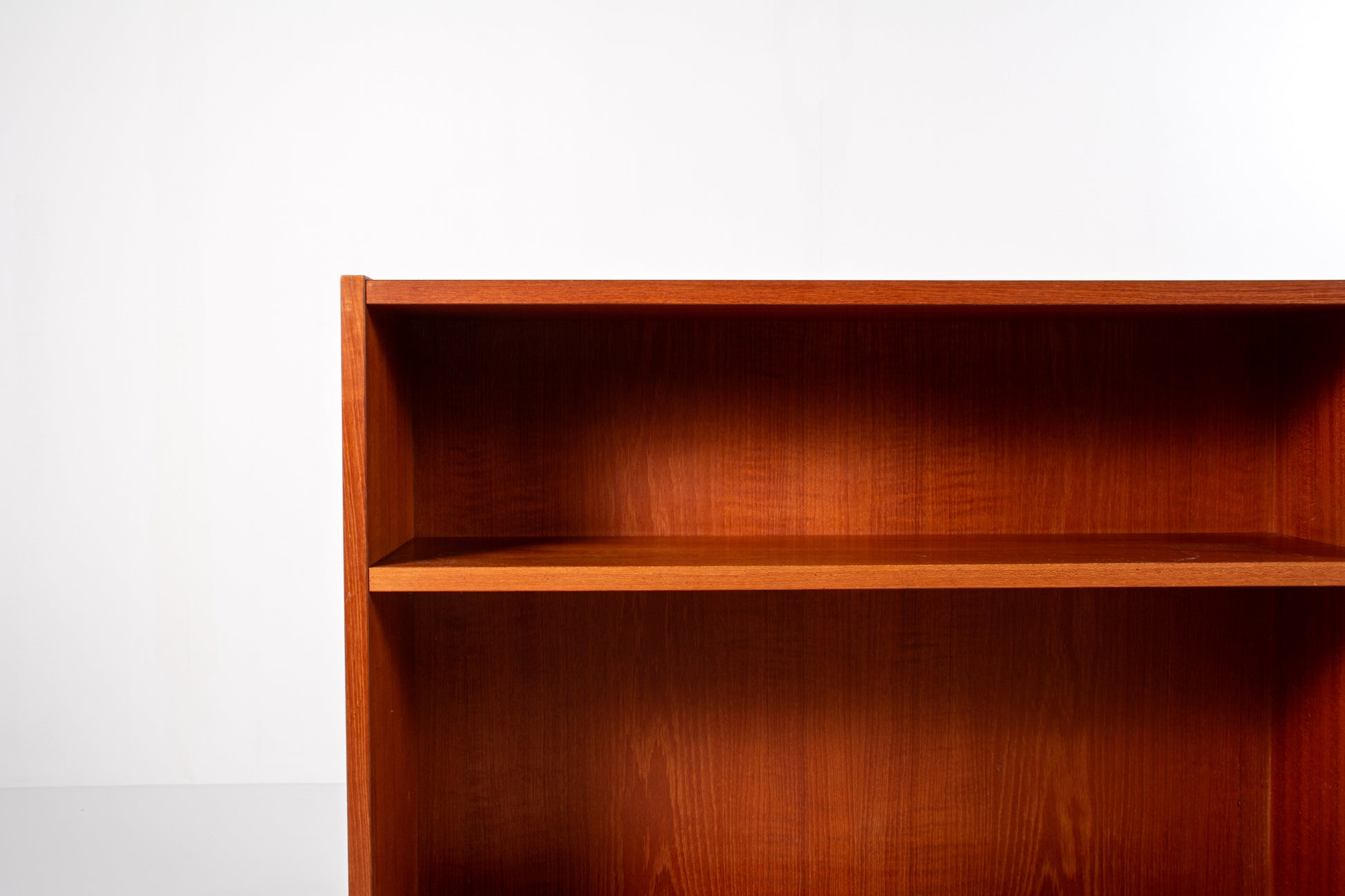 nterior shelves of Danish mid-century teak bookcase showing warm wood grain
