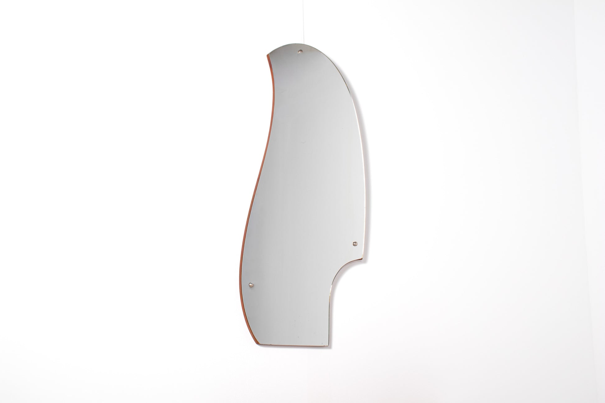 Asymmetrical sculptural mirror above teak lowboy dresser