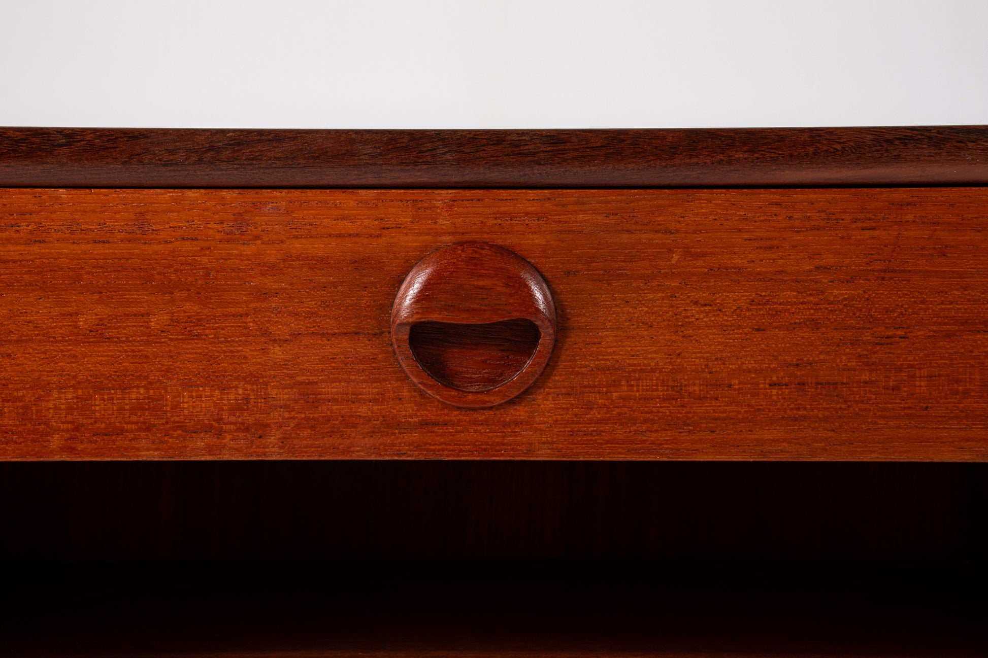 Close-up of sculpted wooden drawer pull on mid-century Danish teak bedside table
